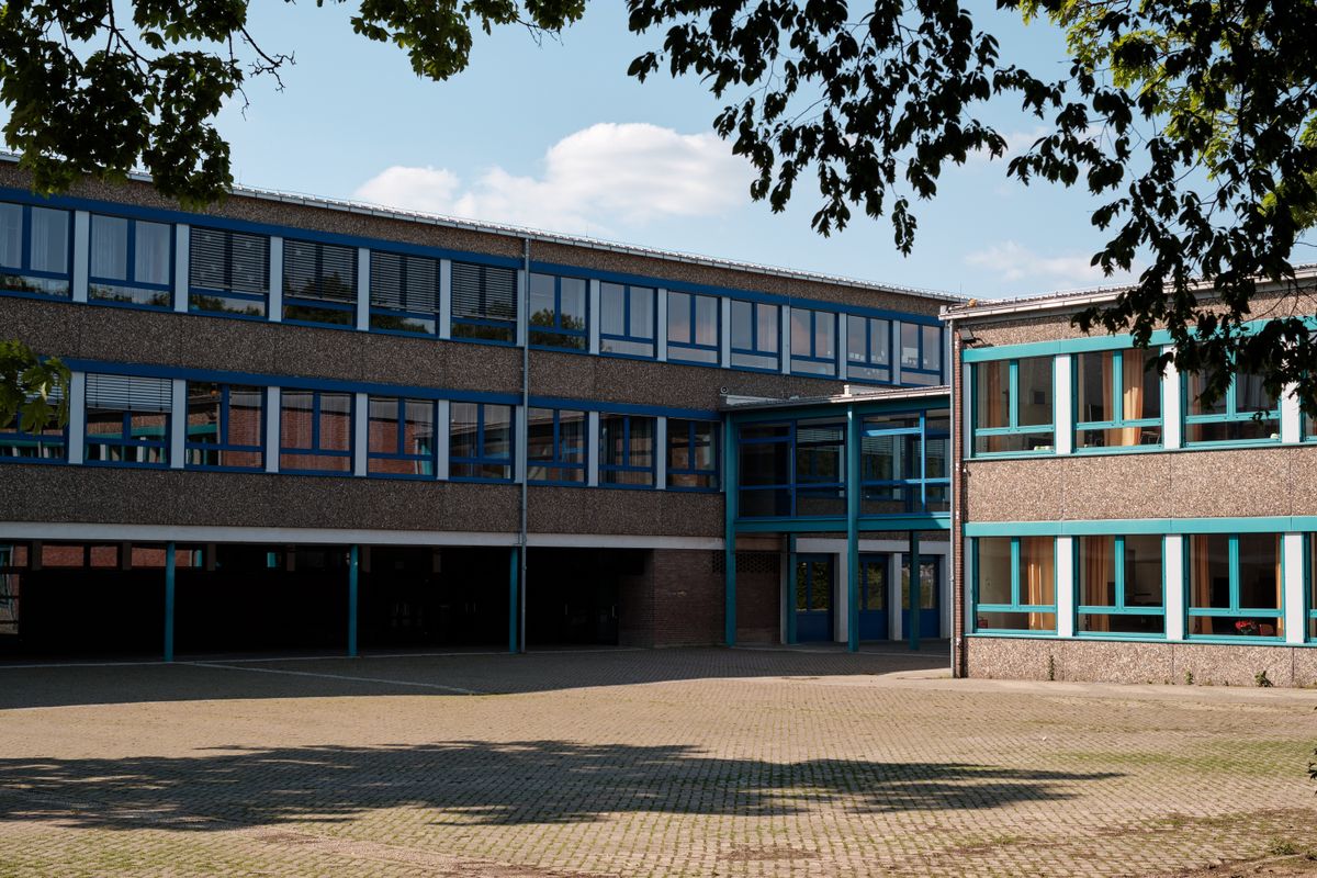 Modern educational building with large windows and a paved courtyard