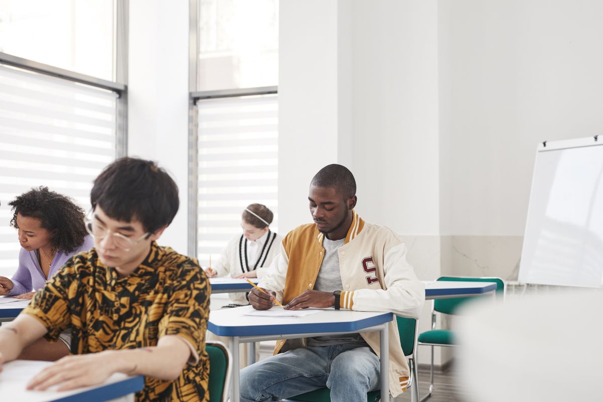 Focused students writing an examination at desks in a classroom