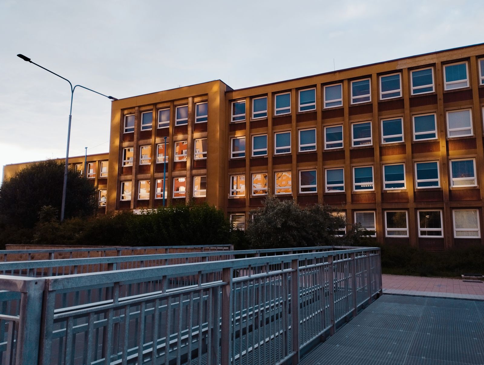 Modern school building illuminated at twilight with a pedestrian walkway