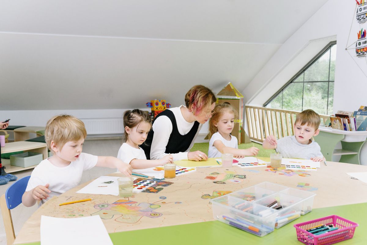 Young children doing an art and craft activity with a teacher in a bright classroom