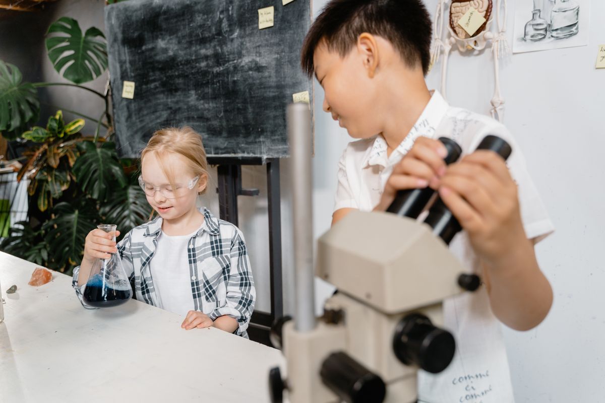 Two young students using a microscope and flask in a science experiment